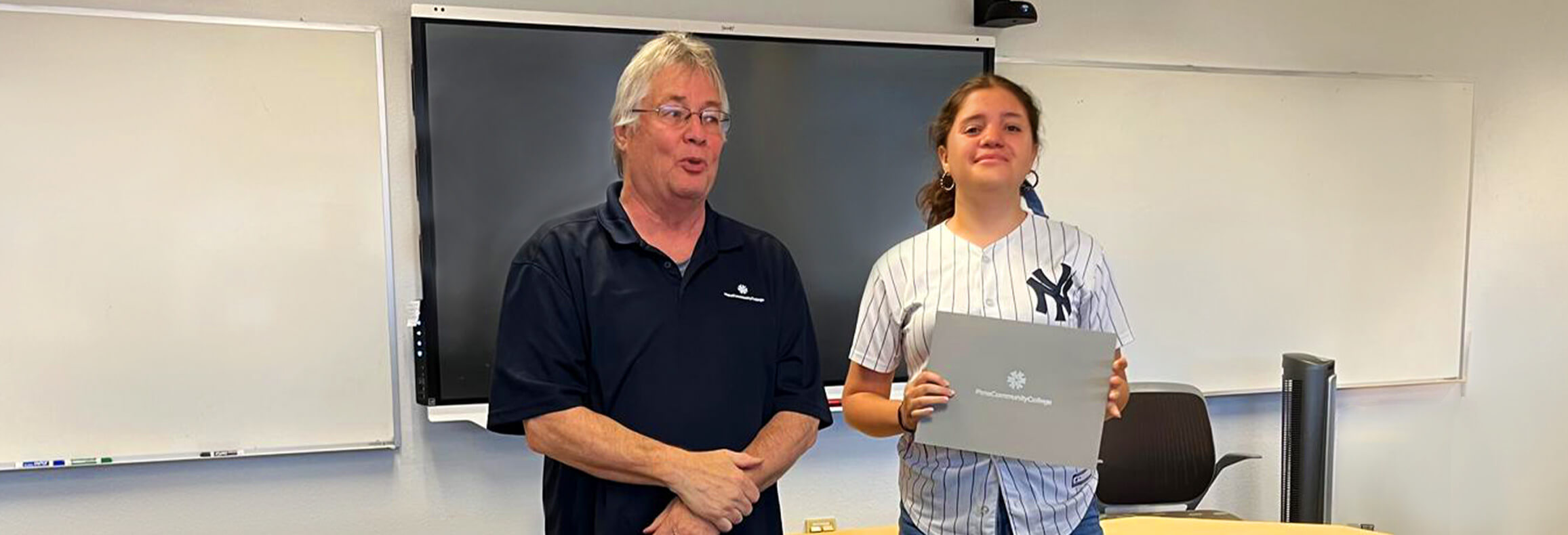 Maynett Godoy Hernandez stands with a teacher in a classroom