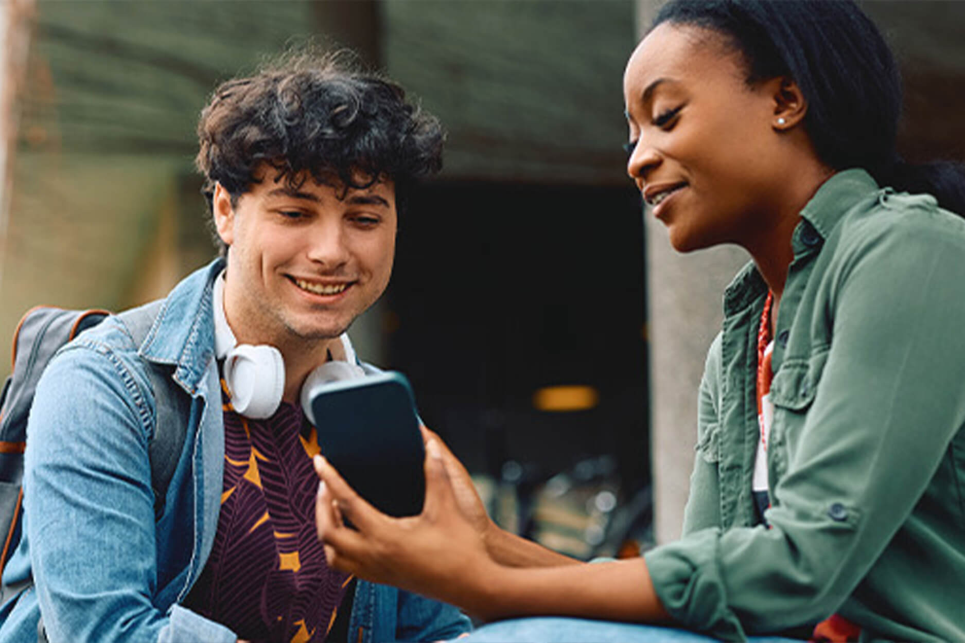 A student shows another student her tablet on campus steps