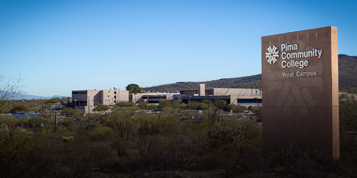 An outside shot of the PCC West Campus sign with the westcampus in the landscape in the background.