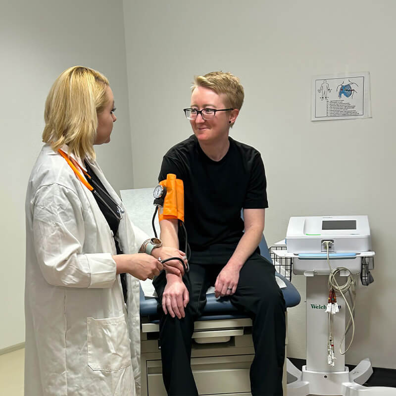 Kailey Sits on a medical table in a classroom running tests with another student
